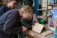 Schüler bohrt mit einer Bohrmaschine ein Loch in eine Holzplatte