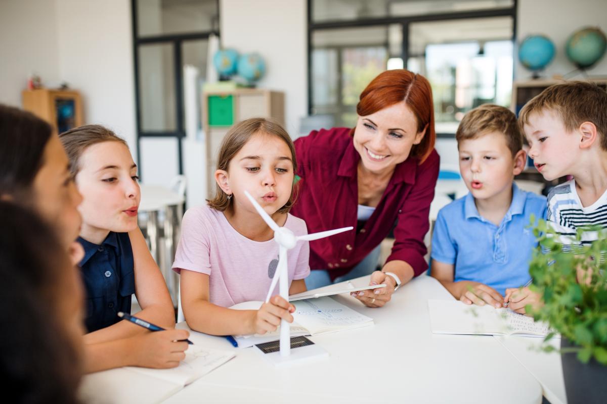 Schülerinnen mit Lehrerin um ein Windkraftmodell gruppiert