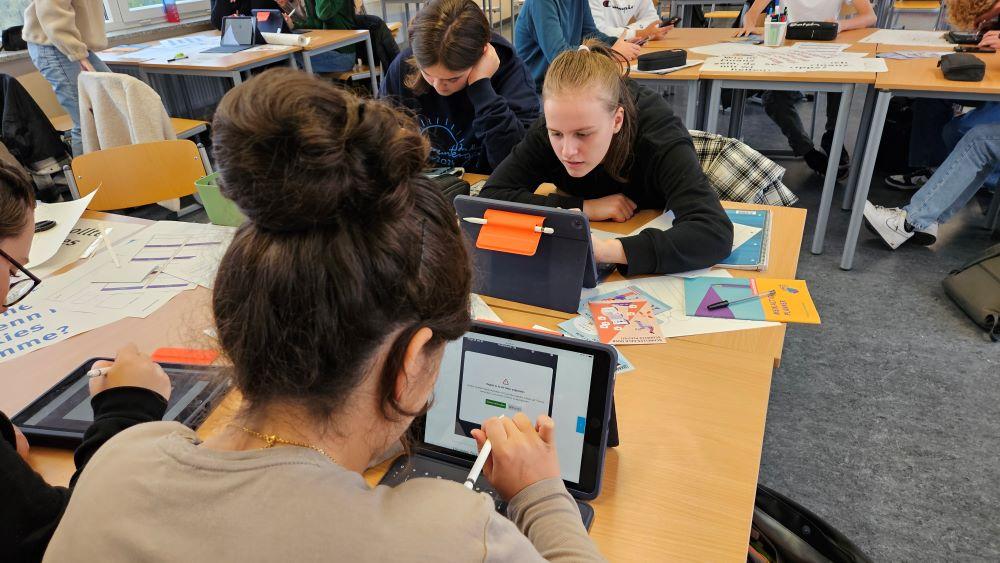 Schüler:innen arbeiten in einer Gruppe an einem Projekt und nutzen Tablets.