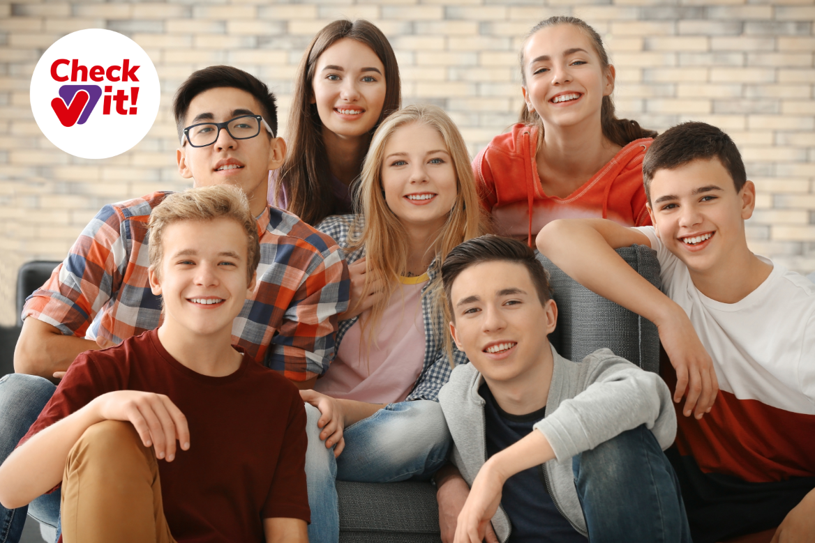 Sieben junge Menschen sitzen zusammen und lächeln.