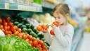 Kind riecht an Gemüse im Supermarkt