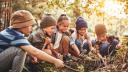 fünf Kinder sitzen draußen in der Natur