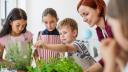 Eine Gruppe Kinder beschäftigt sich zusammen mit ihrer Lehrerin im Unterricht mit verschiedenen Kräutern.