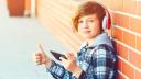 Teenager mit Kopfhörer und Handy streckt einen Daumen nach oben
