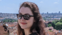Junge Frau mit Sonnenbrille schaut lächelnd in die Kamera