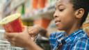 Junge im Supermarkt liest die Zutatenliste auf einem Produkt