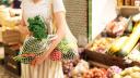 Frau steht im Supermarkt und hat ihr loses Gemüse in Baumwollnetzen.