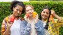 drei jugendliche Mädchen halten Gemüse in die Kamera