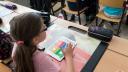 Mädchen sitzt im Klassenzimmer und arbeitet mit einem Tablet